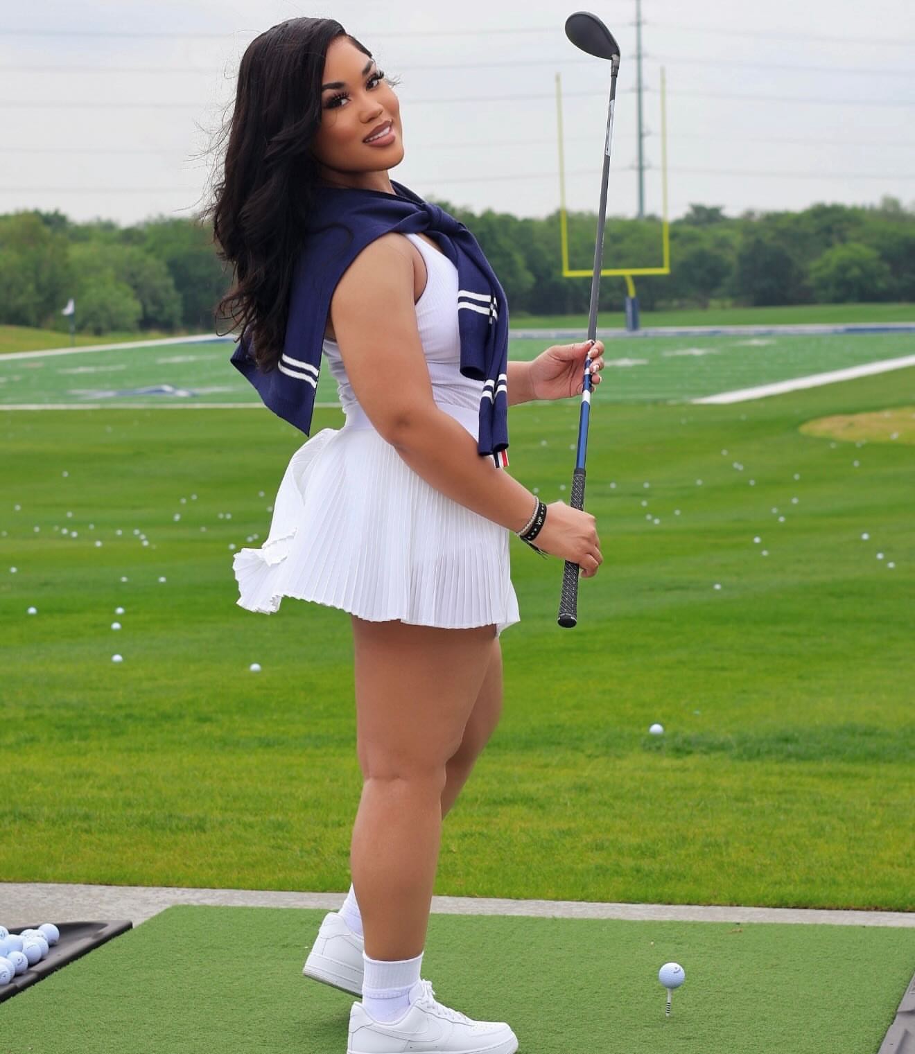Member in white golf attire at the driving range
